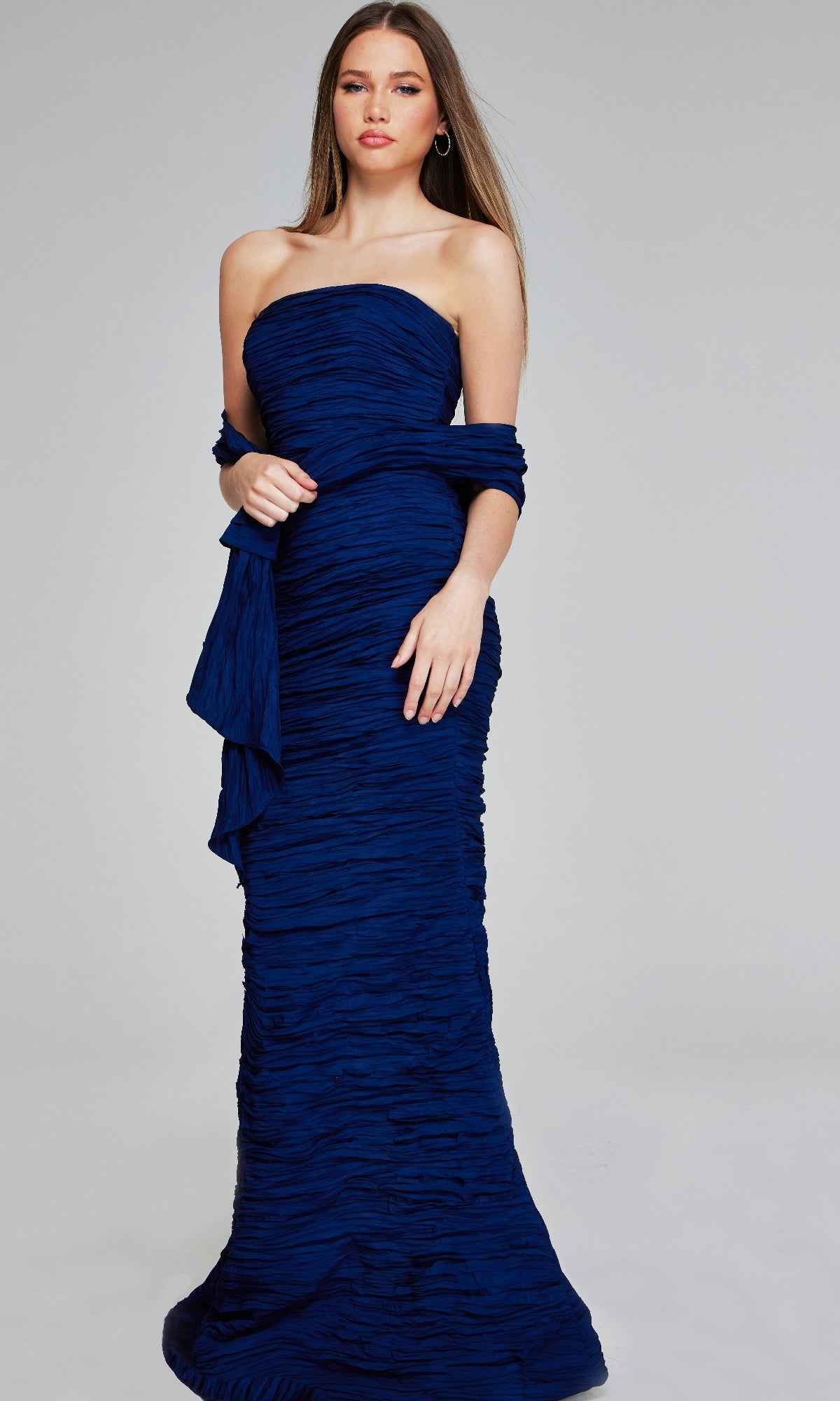 A woman wears the Jovani 40045 long formal dress, a strapless, floor-length gown featuring elegant ruching and a matching wrap, posed against a plain light background.